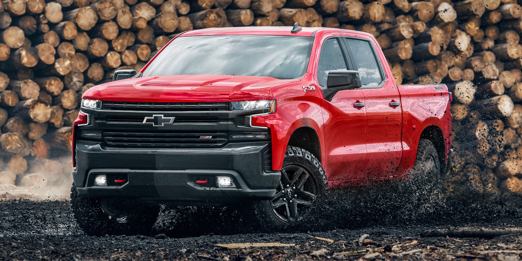 Front-side view of a red 2022 Chevrolet Silverado 1500 vehicle driving in mud